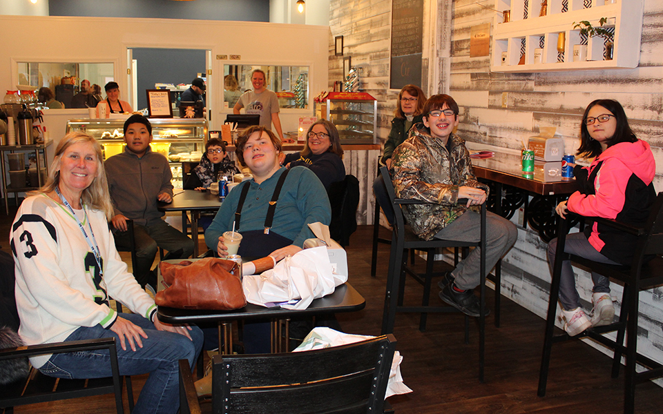 students and adults sitting at tables in a small cafe
