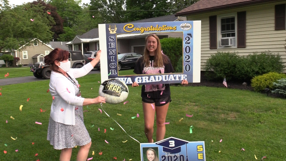 Ms. Kramas & student in front yard, balloon, sign