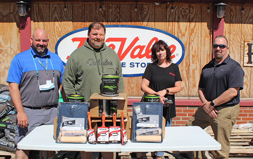 Outdoors, four people, table with paint supplies, True Value Hardware sign