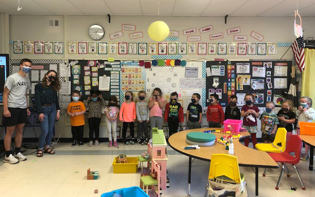 group photo of small children, teacher, and two high school students, masked