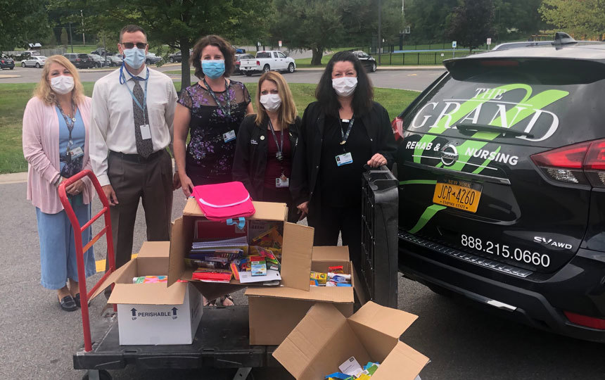 Outdoors, five people, cart filled with boxes, back of car