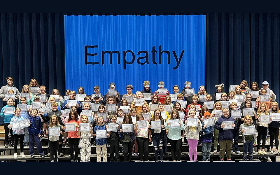 Large group of students on risers with giant empathy sign
