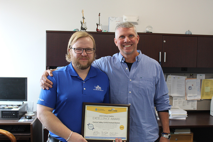 Two men smiling, office, holding plaque
