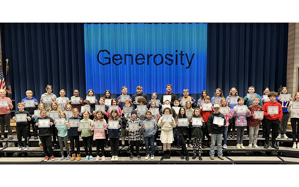 large group of students on risers, holding certificates, in front of generosity banner