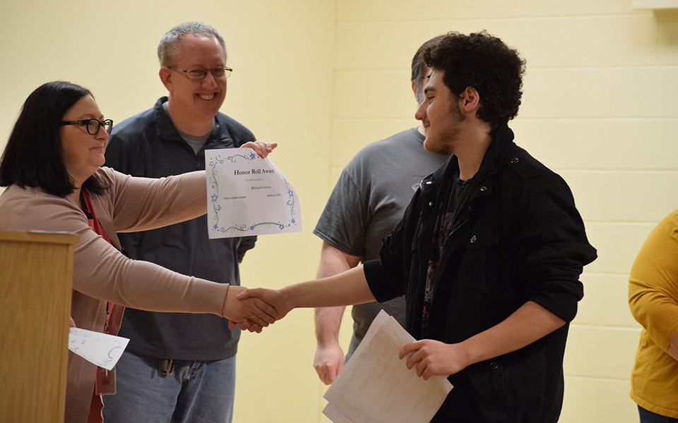 Michael Grecco accepts his certificates from smiling woman, 3 others watching and smiling