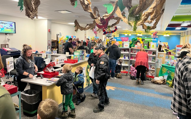 library filled with people, dinosaur decorations, books