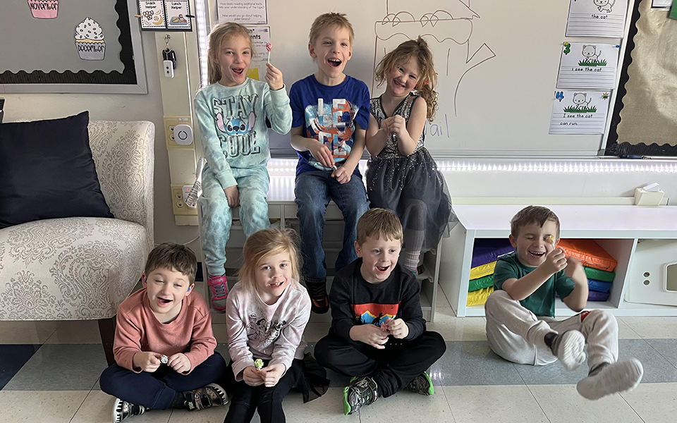 7 children with lollipops, chair, whiteboard