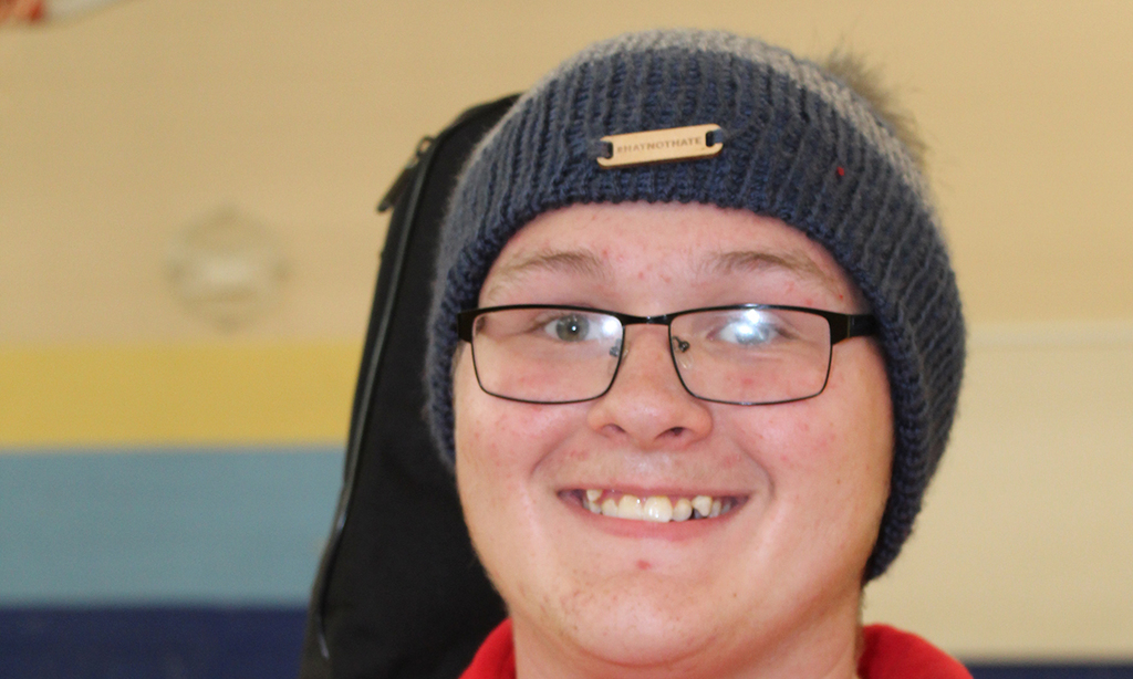 student smiling, blue hat, glasses