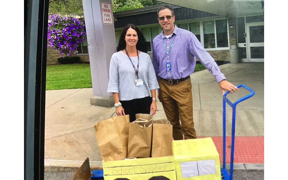 man, woman, cart with bags. outdoors, school front.