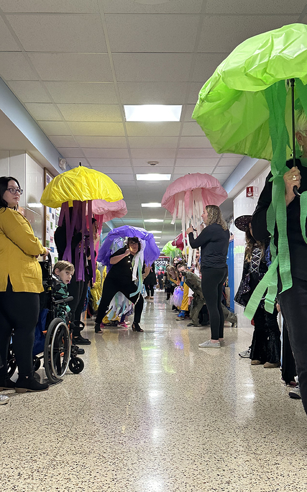 school hallway lined with students in Halloween costumes
