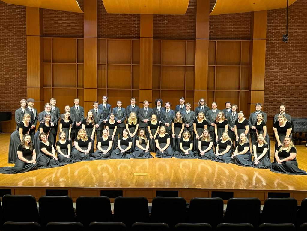 large group of people dressed in black posing on a big stage