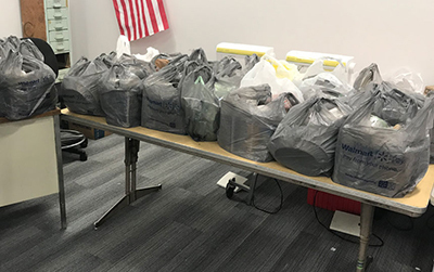 dozens of filled plastic bags piled on a table