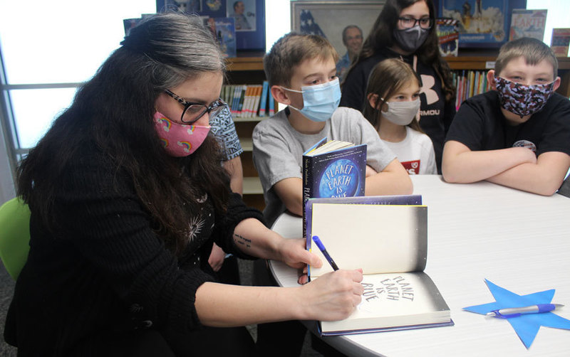 woman at library table signing book