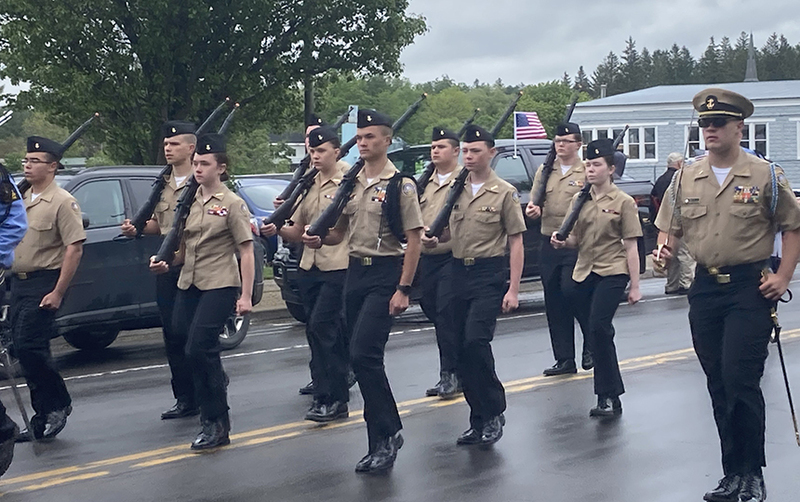 cadets in uniform marching in formation, outdoors, street, rain, trees