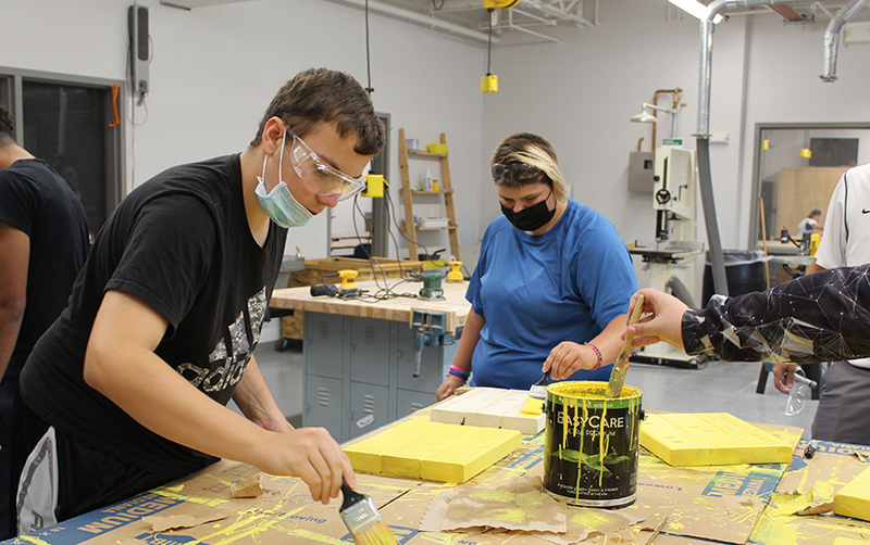 Student in technology class painting stool seats yellow