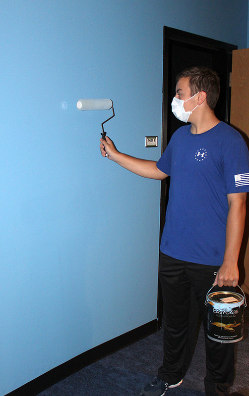 student painting wall with roller
