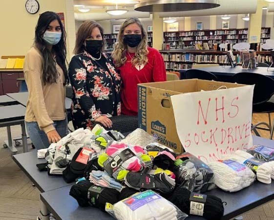 three people, masks, library, pile of socks