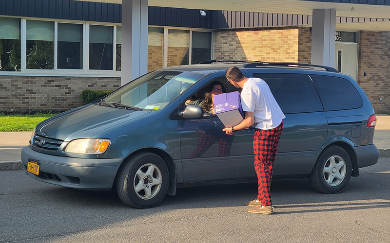 man with box talking to driver of minivan