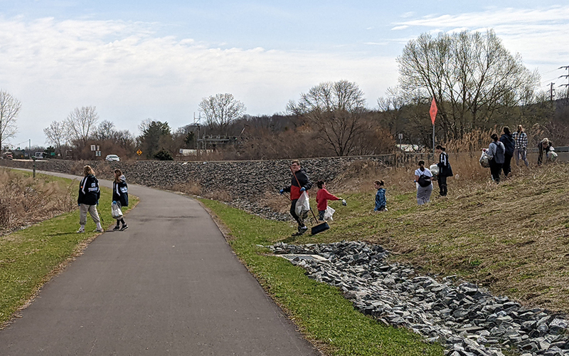 people along path picking up trash, grass, trees