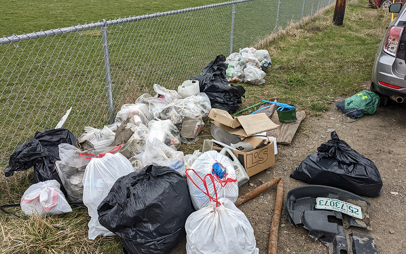 large collection of trash, outdoors, grass, chain link fence