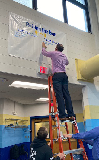 man on ladder placing name on banner