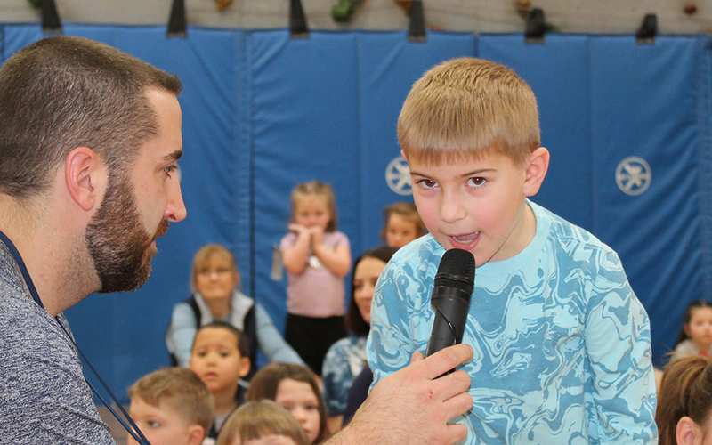 boy speaking into microphone, man holding mic, gym