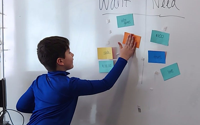 student arranging index cards printed with words on whiteboard