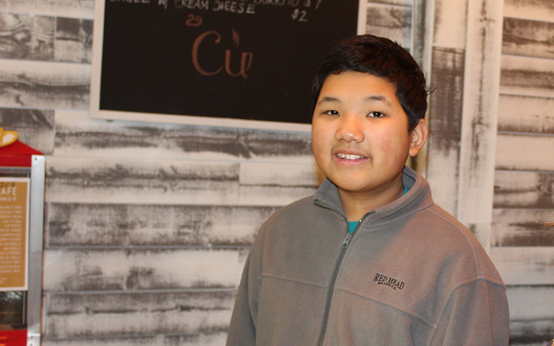 boy smiling in front of chalkboard menu