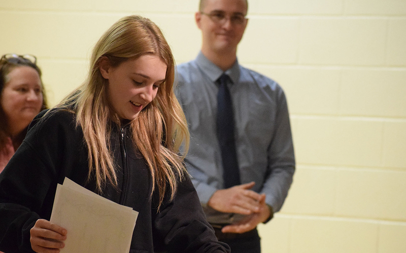 girl smiling, papers in hand, man and woman smiling