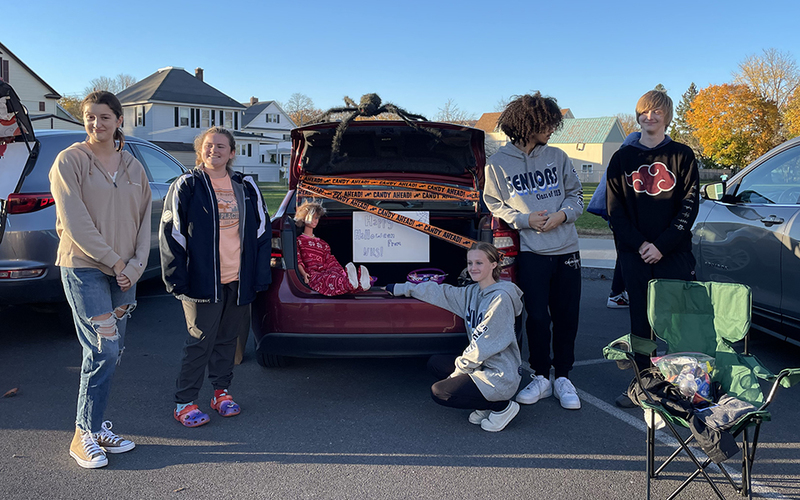 car with open trunk filled with candy, five students, halloween decoratins