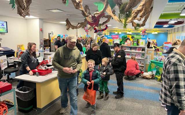 library filled with people, books, dinosaur decorations