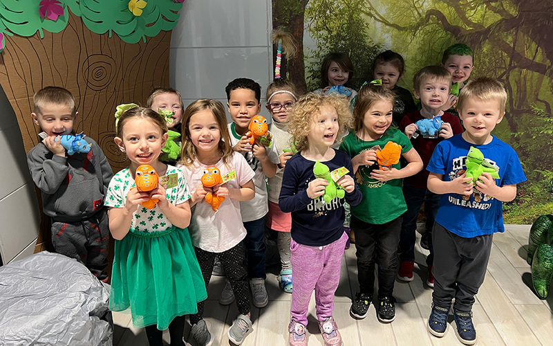 little children standing holding little stuffed dinosaurs