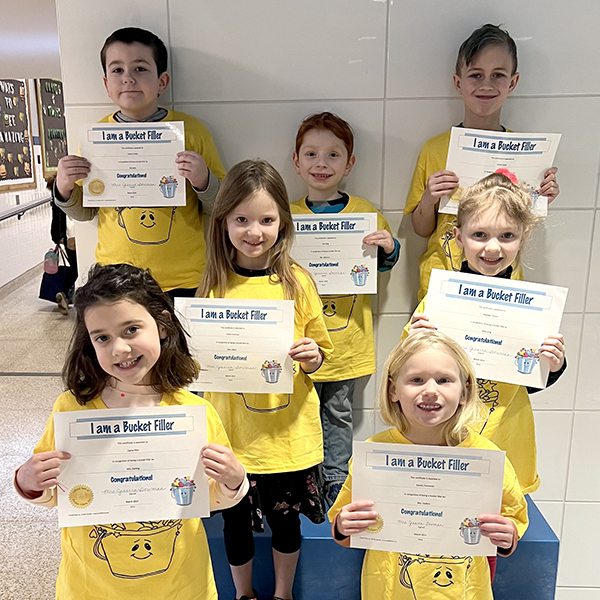 7 students in matching shirts smiling holding certificates