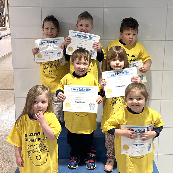 7 students in matching shirts smiling holding certificates