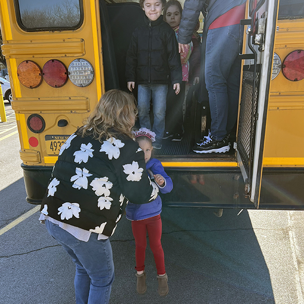 open rear bus emergency door, 2 adults helps students exit.