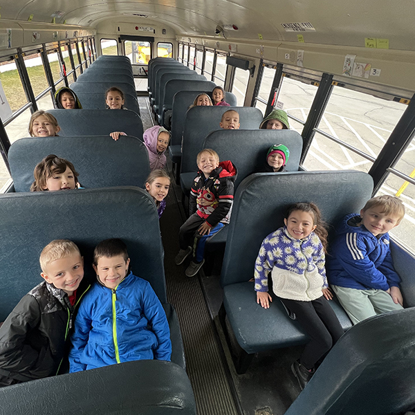 students seated and smiling in school bus