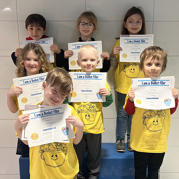 7 students wearing matching t-shirts and holding certificates