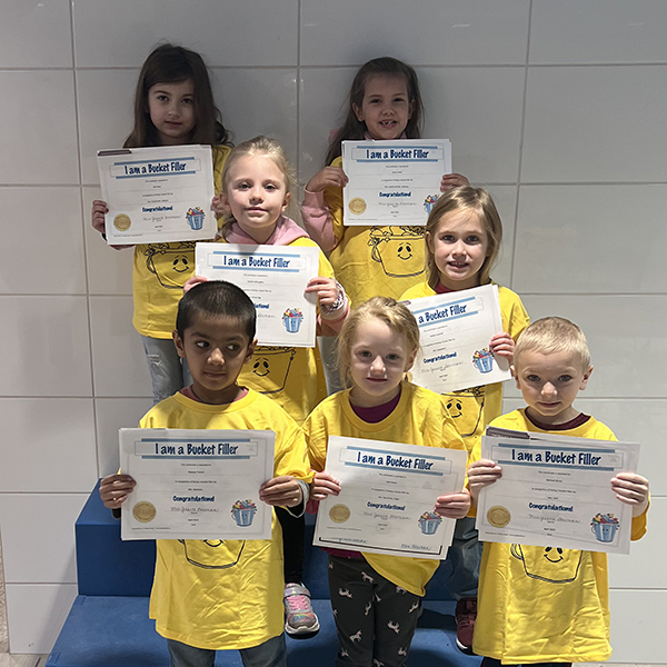 7 students wearing matching t-shirts and holding certificates