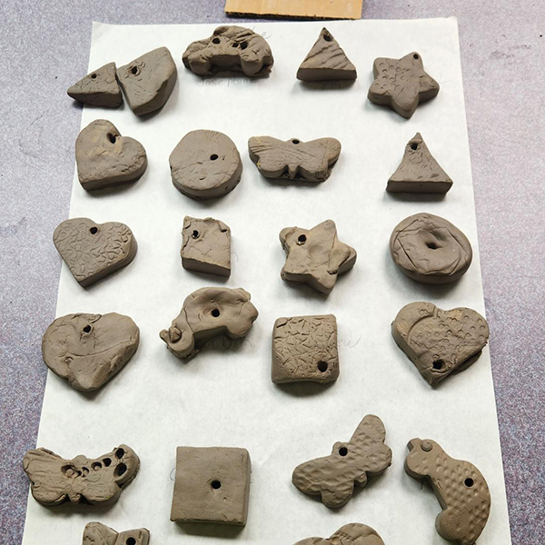 clay cut outs arranged on large sheet of paper. Different shapes such as stars, hearts, triangles, circles, and butterflies.