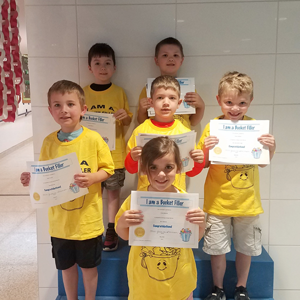7 students in matching shirts holding up certificates