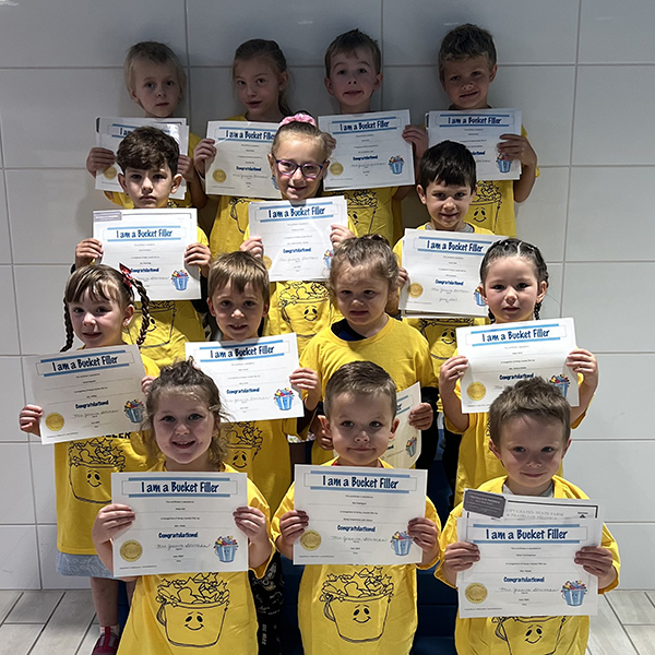 14 smiling children holding certificates