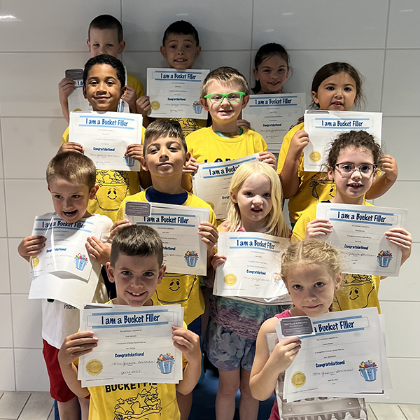 12 smiling children holding certificates