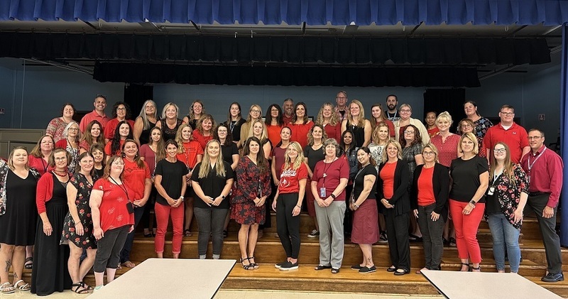 large group of teachers and staff standing in front of stage