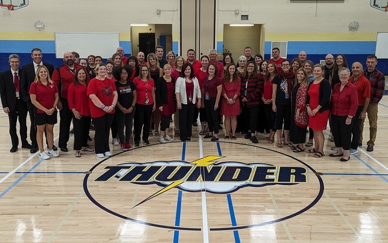 large group of teachers and staff standing in middle of gym floor